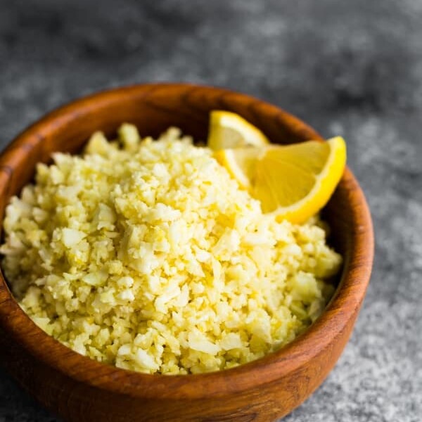 Lemon garlic cauliflower rice in a wood bowl with lemon slice garnish